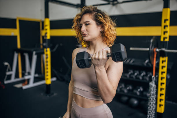 istock Empowered woman lifting dumbbell in modern gym 2176485036