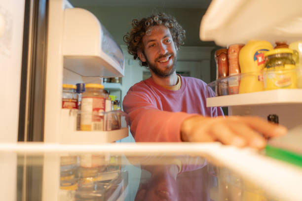 istock Man looking for produce inside the fridge 2176486074