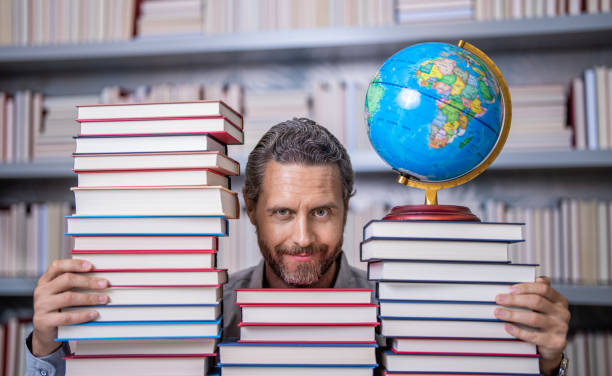 istock nerd man in classroom. bookworm in school library. education and knowledge. man teacher in class. school education. man nerd with school book. school literature education. Dive into a book 2176487435