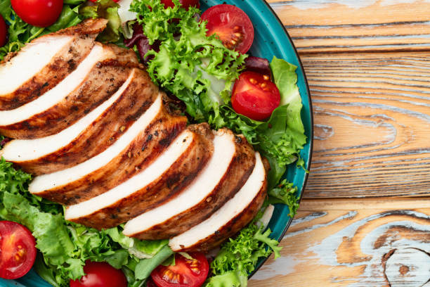 istock Grilled chicken breast ( fillet ) with lattuce salad and cherry tomatoes . Top view 2176495942