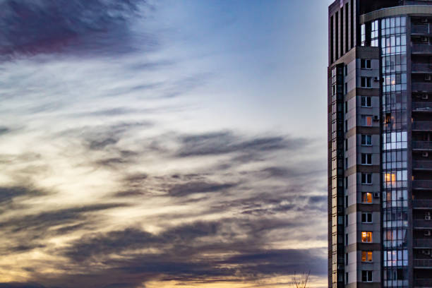 Purple shades are visible in the sunset sky with clouds, they are beautifully combined with the color of a modern multi-storey building located on the right side of the frame.