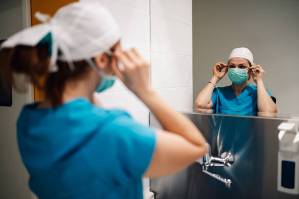 istock Medical professional preparing for surgery, adjusting cap in mirror. 2176503039