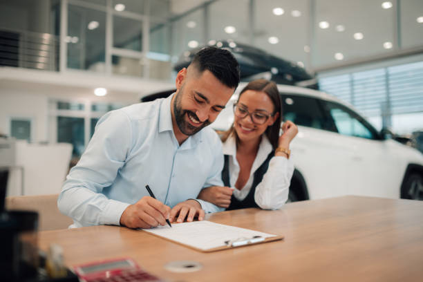 istock Couple joyfully signs agreement, securing new car purchase. 2176505366