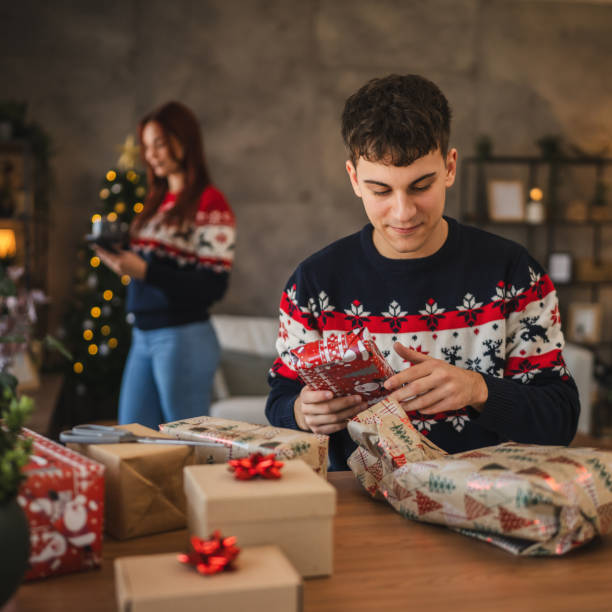 istock young man wrap Christmas gift with festive decorations at home 2176507315