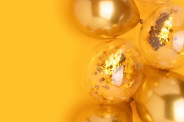 istock Golden air balloons with confetti inside on a yellow background. 2176508569