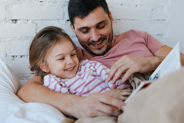 istock Happy Father and Daughter Reading Together in Bed 2176509745