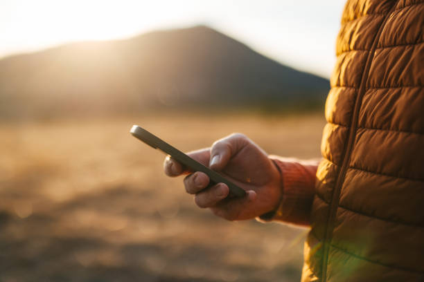 istock Person Using Smartphone in Mountain Landscape at Sunset 2176509891