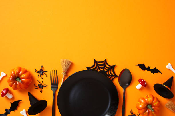 istock Halloween table setting with pumpkins, fly agarics, witch hats, bats, spiders, and spooky decorations on an orange background 2176513392