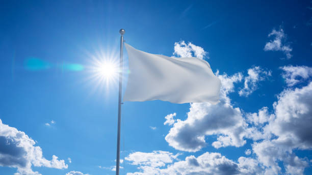 White flag waving on pole, bright sun in the blue summer sky on the background