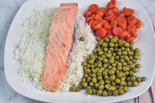 baked salmon served on rice with carrots and peas