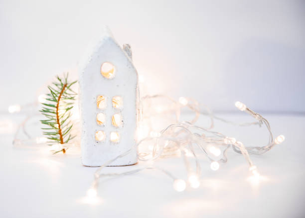 istock Christmas minimalistic decor from a small ceramic house and New Year's white lights on a white background 2176521570