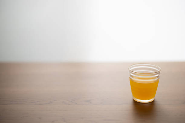 a glass of orange juice put on a wooden tablewith beside a window