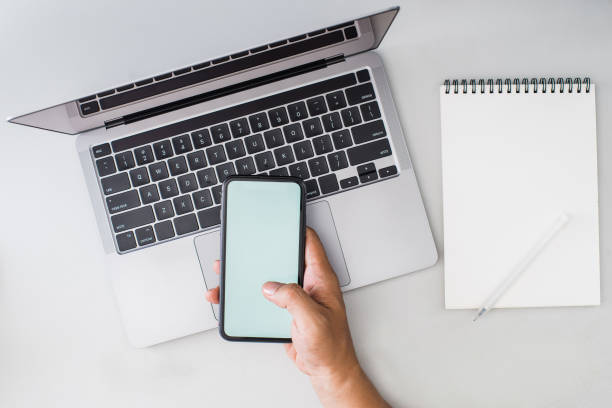 istock Overhead image of person looking on a phone while working in front of a laptop 2176545664