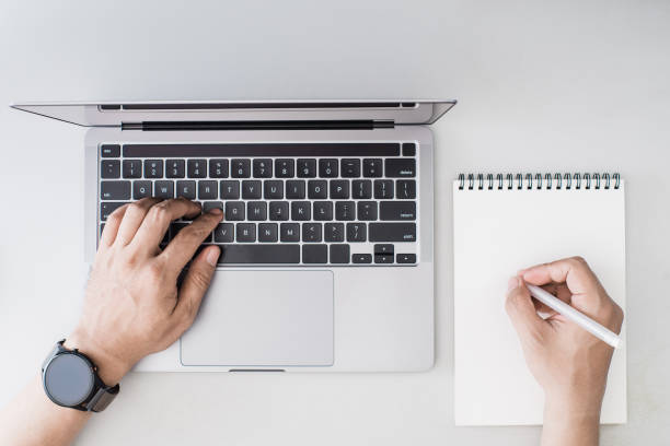 istock Overhead image of person working on a laptop while writing something on paper 2176545671
