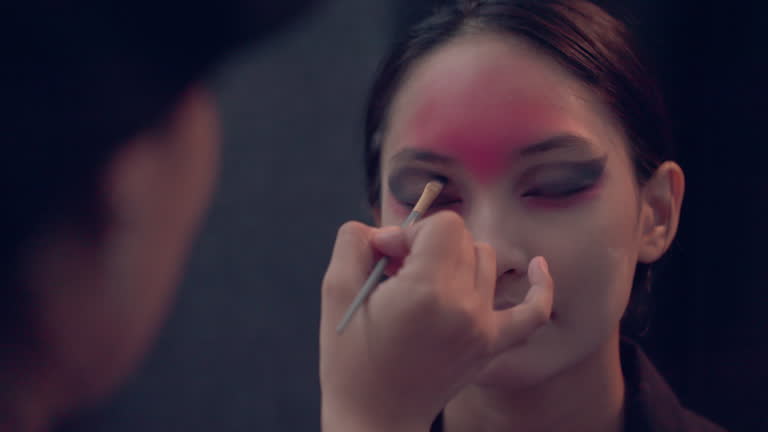 Happy Halloween.A makeup artist is creating scary faces for trick-or-treaters, such as ghosts or the devil, on Asian young men and women.4k footage.