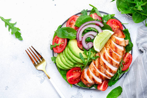 istock Grilled chicken fillet with avocado, spinach and tomato garnish, white background, top view 2176558662