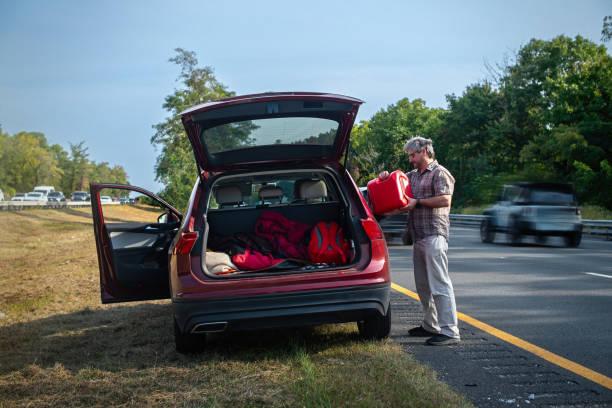 istock Refueling stranded vehicle. Driver pours gas from red canister into SUV on highway shoulder 2176565712
