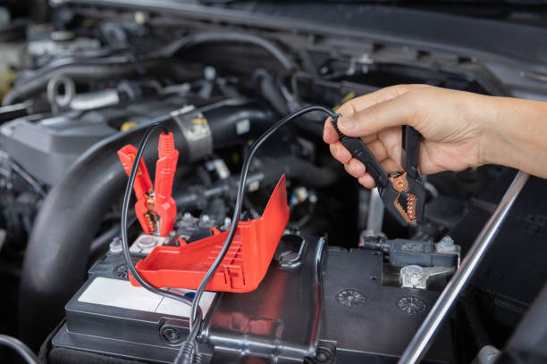 Senior Woman is jumping charger cable to AGM battery on car. Senior Woman is jumping charger cable to AGM battery on car. Battery, Charging, and Starting Systems stock pictures, royalty-free photos & images