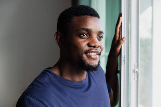 istock A Man Smiles While Standing by a Window, Enjoying the Warm Afternoon Light in a Modern Indoor Space 2176582669