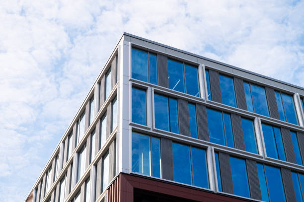 istock Low-angle view of a modern office building with glass windows against a blue sky 2176597570