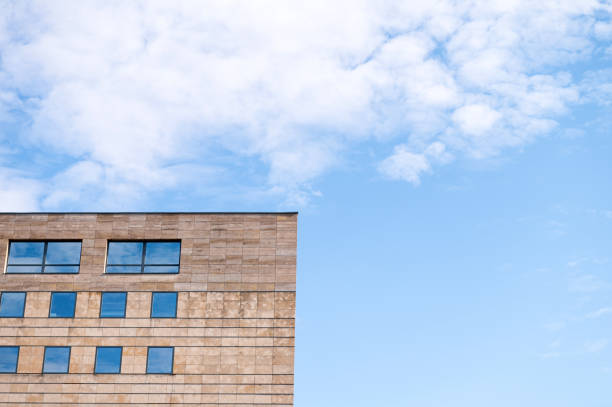 Modern building facade with large windows against blue sky with clouds. Architectural design concept