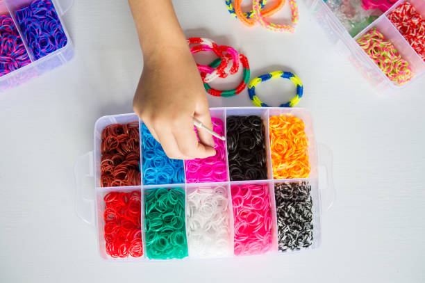 istock Hand picking colorful rubber bands from storage box on white table. 2176597611