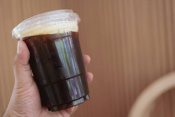 Man hand holding ice black coffee in clear plastic cup