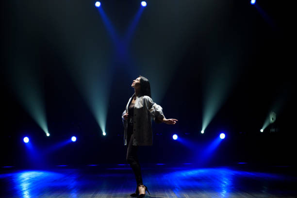 istock Girl in black suit performing on stage with bright blue background 2176598188