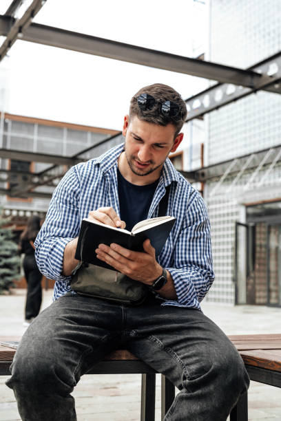 istock A person writes in a notebook while sitting on a park bench 2176599034