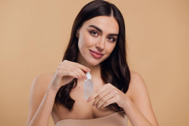 istock Woman Dropping Serum on Face on Beige Background 2176612559