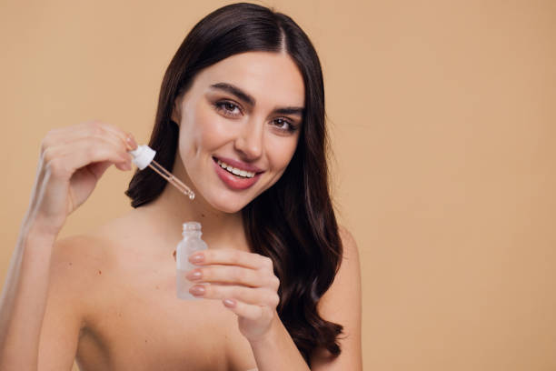 istock Woman Dropping Serum on Face on Beige Background 2176612998