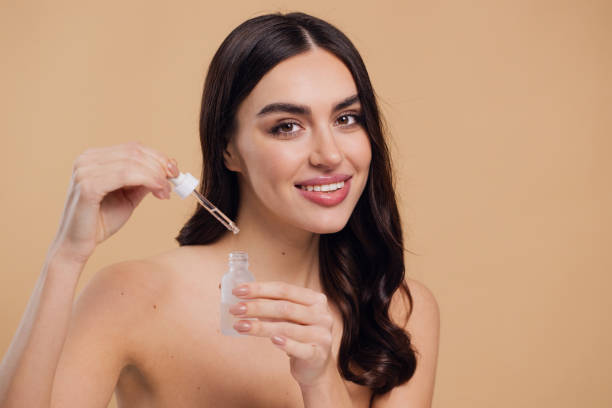 istock Woman Dropping Serum on Face on Beige Background 2176613001