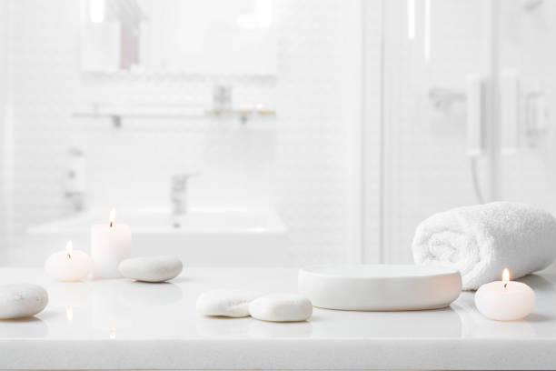 istock Marble table for spa product display with stones, burning candles and towel on blurred bathroom background 2176614343