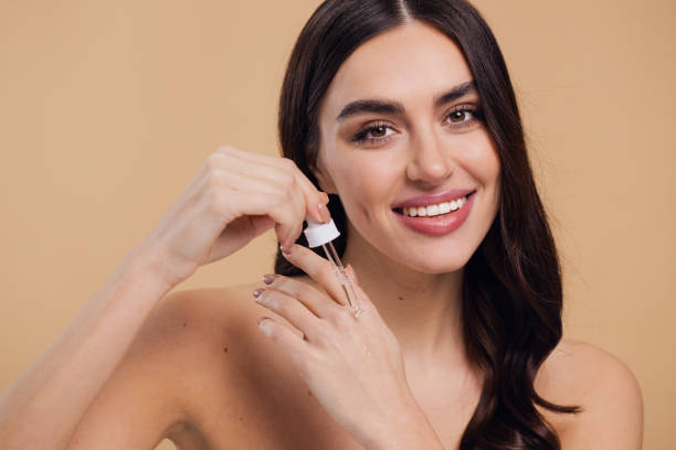 istock Woman Dropping Serum on Face on Beige Background 2176619048