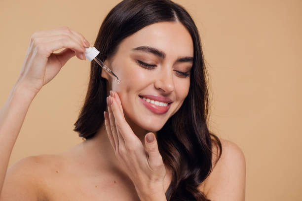 istock Woman Dropping Serum on Face on Beige Background 2176619070