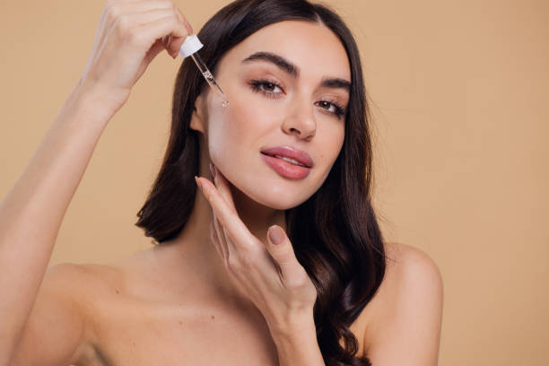 istock Woman Dropping Serum on Face on Beige Background 2176619121