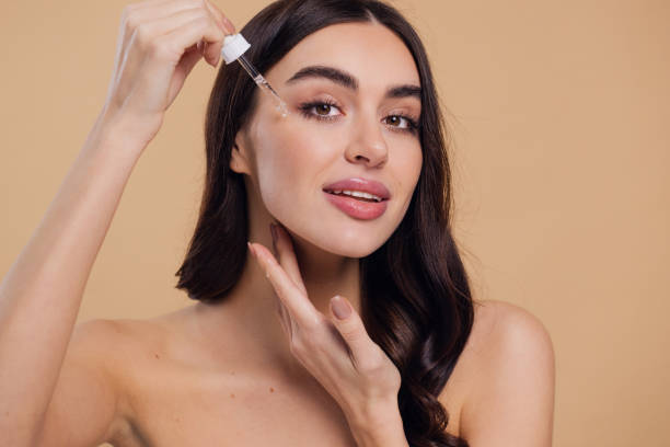 istock Woman Dropping Serum on Face on Beige Background 2176619146