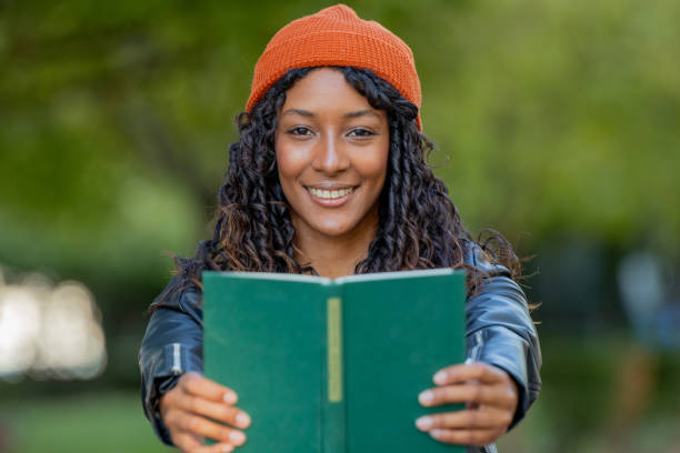 istock young woman with hat in autumn smiling with a book 2176621679