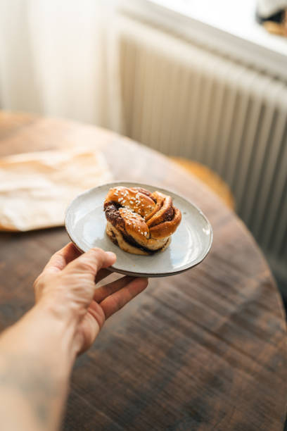 istock Hand holding delicious cinnamon roll on ceramic plate 2176624139