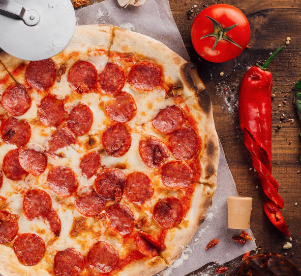istock Delicious pepperoni pizza surrounded by fresh ingredients on wooden table 2176625628