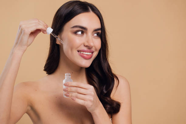 istock Woman Dropping Serum on Face on Beige Background 2176628337