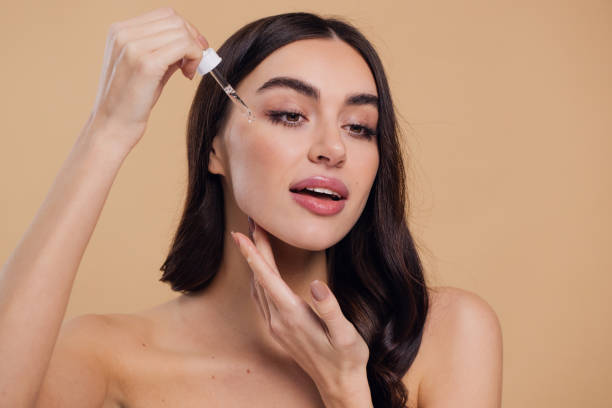 istock Woman Dropping Serum on Face on Beige Background 2176628436