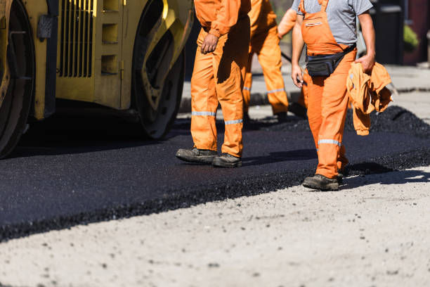 istock Construction workers in orange uniforms paving a road with asphalt during a sunny day in a city 2176629744