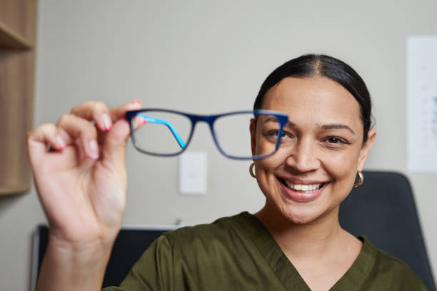 istock Smiling Optometrist Holding Eyeglasses in Office Setting With Eye Chart in Background 2176630706