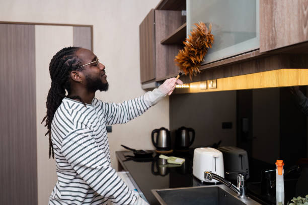 istock Professional Housekeeper Dusting a Shelf with Feather Duster in a Modern Home Interior 2176631391