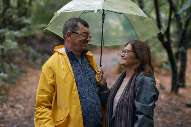 istock Happy embraced senior couple walking with umbrella at forest 2176631476
