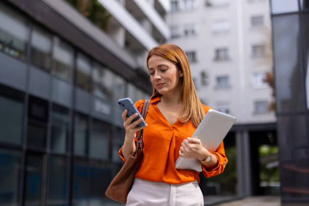 istock Professional woman using her smartphone while strolling through the city 2176632457