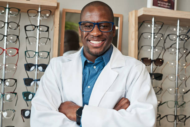istock Confident Optometrist Smiling in Optical Store with Eyeglasses Displayed in Background 2176637352