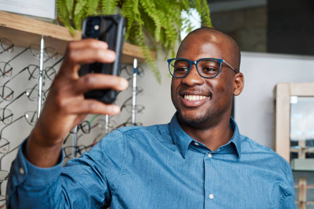 istock Smiling Optometrist Taking a Selfie in Eyeglasses Store with Displayed Spectacles 2176639259