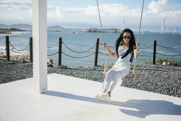 A cute Asian beauty on the swing by the seaside